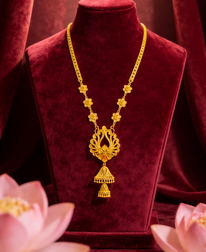 Gold necklace on a red velvet stand with pink flowers in the foreground
